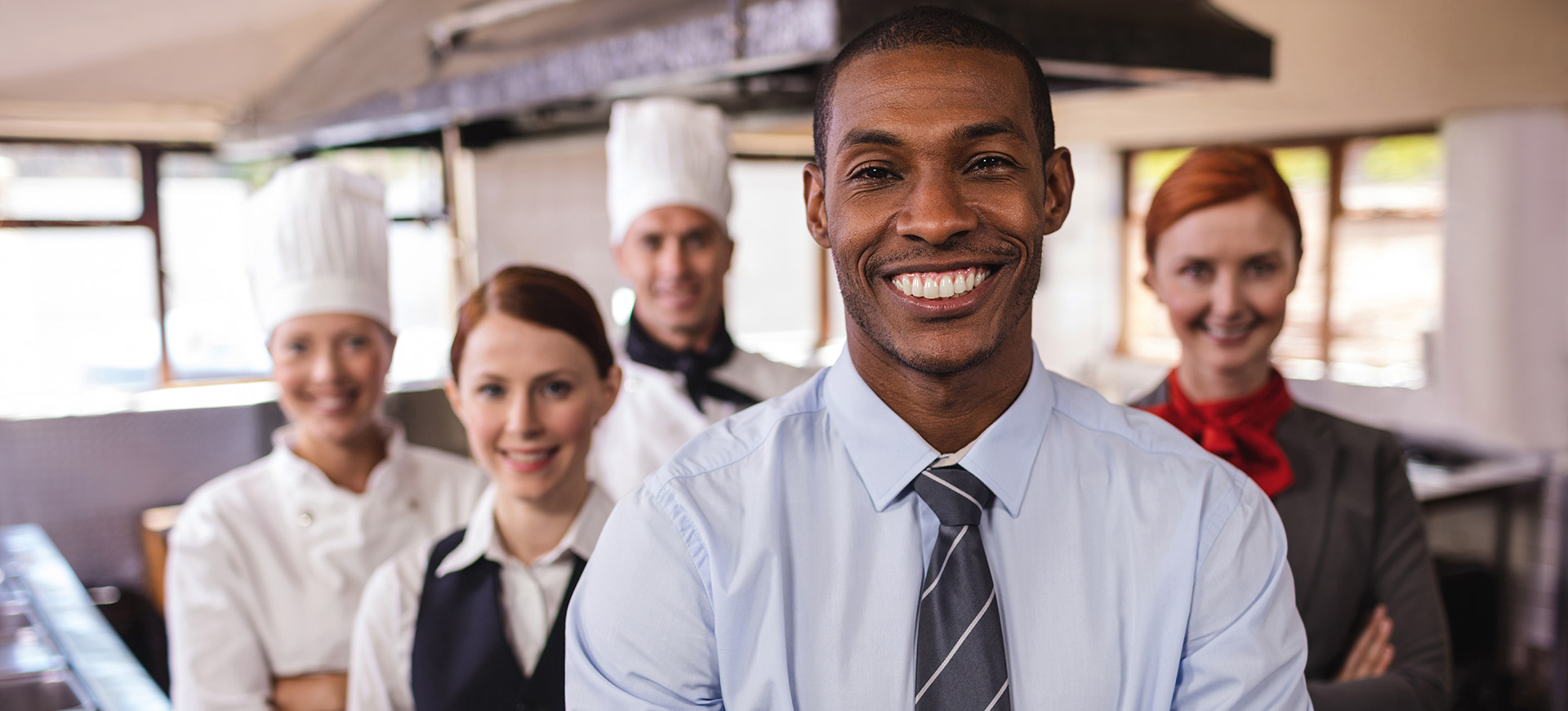 Image of four kitchen workers looking at the camera and smiling